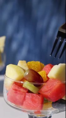 Mavi arka planda bir kase taze meyve salatası, yakın plan yemek, sağlıklı beslenme.