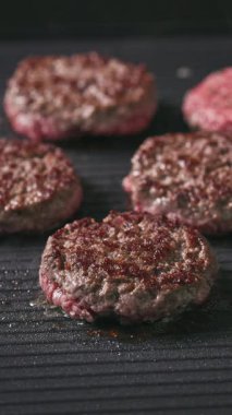 Aşçı, kıymalı burger köfteleri, sıcak, siyah ızgara yüzeyi pişirir.