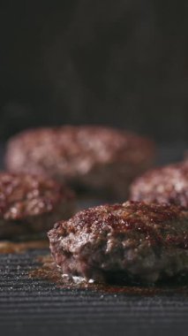 Kıymalı biftek köfteleri sıcak, siyah elektrikli ızgara yüzeyinde pişiyor.