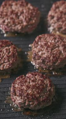 Kıymalı biftek köfteleri sıcak, siyah elektrikli ızgara yüzeyinde pişiyor.