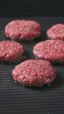 Kıymalı biftek köfteleri sıcak, siyah elektrikli ızgara yüzeyinde pişiyor.