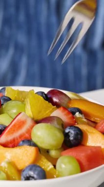 Mavi arka planda bir kase taze meyve salatası, yakın plan yemek, sağlıklı beslenme.