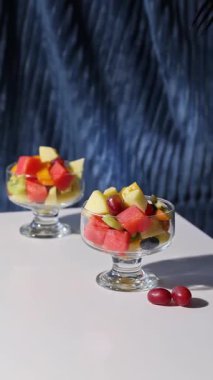 Mavi arka planda bir kase taze meyve salatası, yakın plan yemek, sağlıklı beslenme.