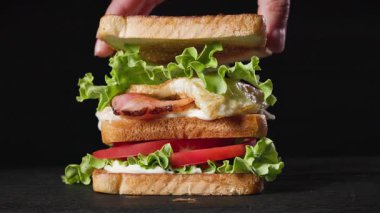 Kulüp sandviçi yapma süreci. Bir aşçı et ve sebzeye kızarmış ekmek dilimi koydu.