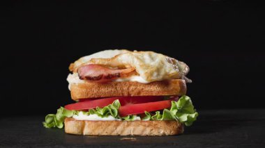 Bir aşçı yeşil marul yaprağını taze ekmek dilimlerinin üzerine, kulüp sandviçi yapmak için, yiyecek yakın çekimi için siyah tahta tahtaya koydu. Sağlıklı yemek yapma süreci