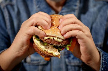 Kırık burger insan ellerinde. Kapatın.