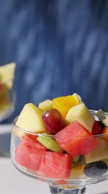 Mavi arka planda bir kase taze meyve salatası, yakın plan yemek, sağlıklı beslenme.