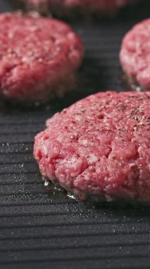 Kıymalı biftek köfteleri sıcak, siyah elektrikli ızgara yüzeyinde pişiyor.