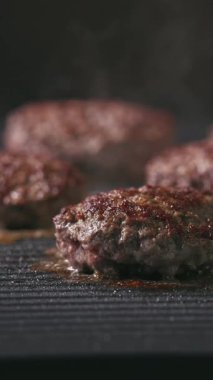 Kıymalı biftek köfteleri sıcak, siyah elektrikli ızgara yüzeyinde pişiyor.