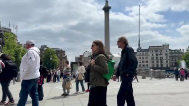 Londra, İngiltere - 18 Mayıs 2025: İnsanlar Trafalgar Meydanı 'nda yürüyor ve güzel güneşli bir bahar gününde Ulusal Galeri' ye doğru canlı performans sergileyen müzisyenlerin şarkılarının tadını çıkarıyor