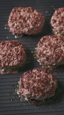 Kıymalı biftek köfteleri sıcak, siyah elektrikli ızgara yüzeyinde pişiyor.