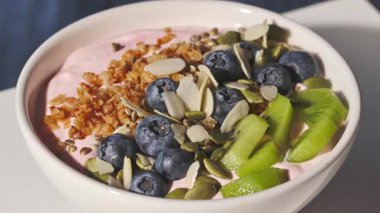 Elinde bir kaşıkla yoğurt, taze meyveler, meyveler ve müsli, yakın plan yemek, sağlıklı kahvaltı.