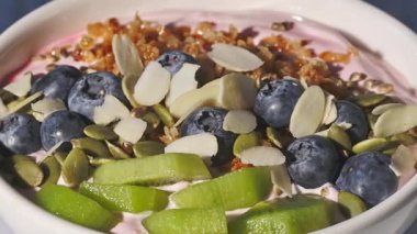 Yoğurtlu beyaz kahvaltı kasesi ve mavi arka planda meyveler, yakın plan yiyecekler, sağlıklı beslenme.