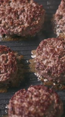 Kıymalı biftek köfteleri sıcak, siyah elektrikli ızgara yüzeyinde pişiyor.