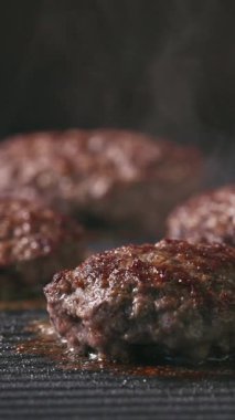 Kıymalı biftek köfteleri sıcak, siyah elektrikli ızgara yüzeyinde pişiyor.