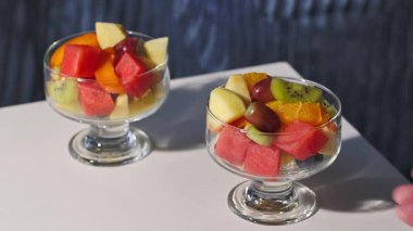 Taze meyve salatasıyla dolu beyaz kâse insan eliyle masadan kaldırıldı, sağlıklı yemek. 