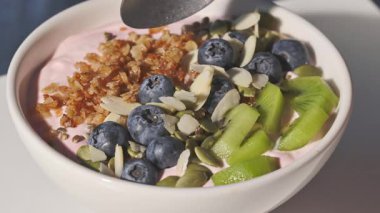 Elinde bir kaşıkla yoğurt, taze meyveler, meyveler ve müsli, yakın plan yemek, sağlıklı kahvaltı.