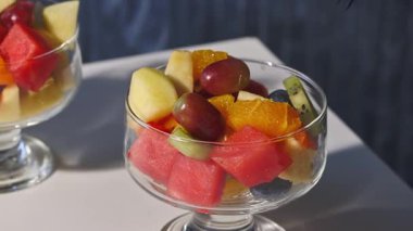 Mavi arka planda bir kase taze meyve salatası, yakın plan yemek, sağlıklı beslenme.