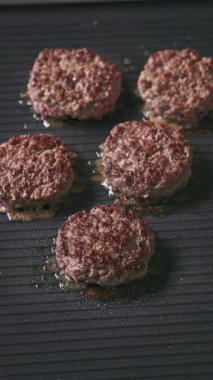 Kıymalı biftek köfteleri sıcak, siyah elektrikli ızgara yüzeyinde pişiyor.