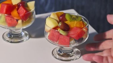 Taze meyve salatasıyla dolu cam kase insan eliyle masadan kaldırıldı, sağlıklı yemek. 