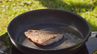 Açık hava yemekleri. Pişirmek sıcak tavada taze balık filetosu hazırlamak yağlı bahçede lezzetli yemekler yapmak için kapalı yemek, açık hava ışığı
