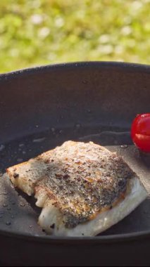 Açık hava yemekleri. Pişirmek sıcak tavada taze balık filetosu hazırlamak yağlı bahçede lezzetli yemekler yapmak için kapalı yemek, açık hava ışığı