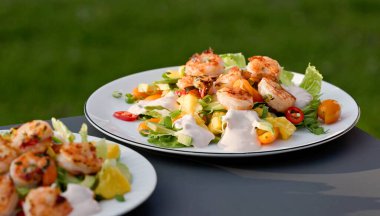 Taze hazırlanmış porsiyon sağlıklı sebze salatası ve ızgara karides. Açık hava yemekleri, yakın plan yemekler.
