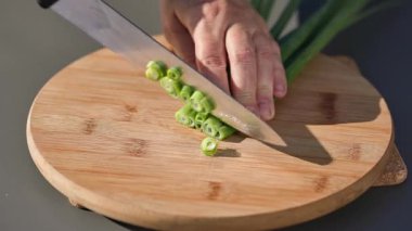 Şef sağlıklı bir yemek hazırlamak için taze yeşil soğan keser. Açık hava yemekleri, yakın mesafe yemekleri.