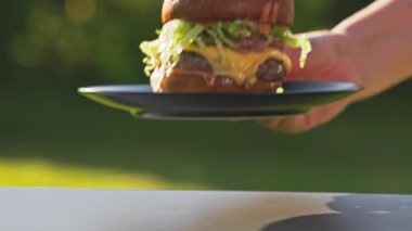 Aşçı masaya taze ızgara burger, erimiş peynir ve soğanlı çörek, tabakta sos, yakın plan yemek, açık hava yemekleri.