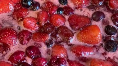 Bir tencerede çeşitli kırmızı böğürtlenler kaynıyor. Ev yapımı reçel yapma süreci, yakın çekim yiyecekler.