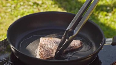 Açık hava yemekleri. Pişirmek sıcak tavada taze balık filetosu hazırlamak yağlı bahçede lezzetli yemekler yapmak için kapalı yemek, açık hava ışığı