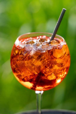 Bir bardak Aperol Spretz kokteyli. Odaklanamayan yeşil bahçe arka planında.