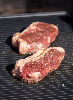 Lezzetli ve sağlıklı yemek yapmak için elektrikli ızgara yüzeyinde taze çiğ biftek.