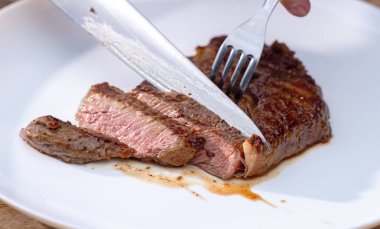 Beyaz tabakta taze ızgara sulu, dilimlenmiş biftek.