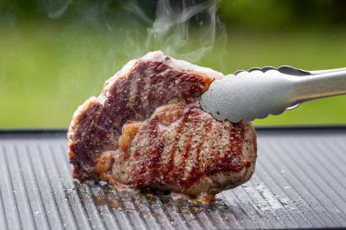 Sıcak elektrikli ızgara yüzeyinde tuzlu ve biberli taze ızgara biftek.