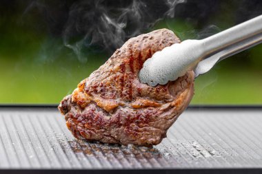 Sıcak elektrikli ızgara yüzeyinde tuzlu ve biberli taze ızgara biftek.