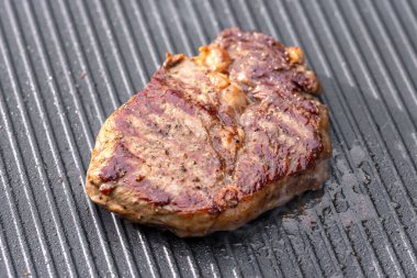 Sıcak elektrikli ızgara yüzeyinde tuzlu ve biberli taze ızgara biftek.