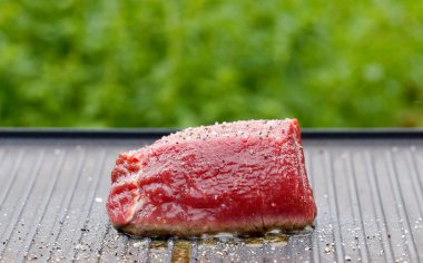 Açık hava yemekleri. Pişirmek taze çiğ sığır filetosu hazırlamak yağlı ve baharatlı biftek ve sıcak ızgara tavada lezzetli yemek yapmak için bahçe, yemek yakın plan, açık hava doğal ışık