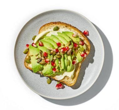 Beyaz arka planda izole edilmiş avokado ve tohumlu sağlıklı kahvaltı sandviçi.