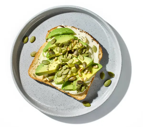 Dilimlenmiş avokado ve beyaz arka planda izole edilmiş tohumlu sağlıklı kahvaltı sandviçi.
