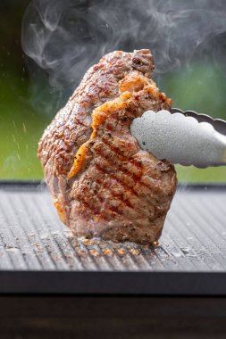 Sıcak elektrikli ızgara yüzeyinde tuzlu ve biberli taze ızgara biftek.