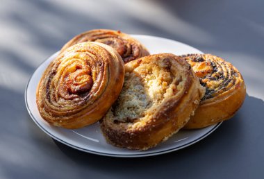 Güneşli gri masada taze pişmiş hamur işleri, açık havada yemek.