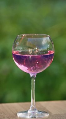 Yeşil bahçe arka planına karşı bir bardak pembe kızılcık kokteyli.