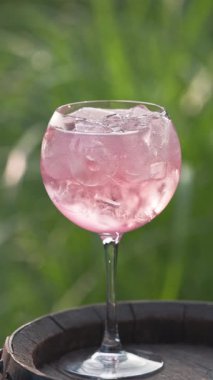 Yeşil bahçe arka planına karşı bir bardak pembe kızılcık kokteyli.