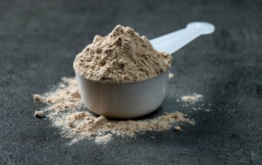 Kepçedeki protein tozu. beyaz spor beslenmesi. Spor ya da diyet içeceği hazırlamak için kuru karışım.