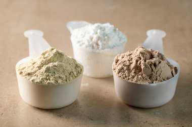 Kepçe içinde protein tozu. beyaz spor beslenmesi. Spor ya da diyet içeceği hazırlamak için kuru karışım.