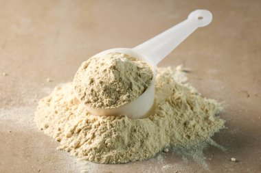 Kepçedeki protein tozu. beyaz spor beslenmesi. Spor ya da diyet içeceği hazırlamak için kuru karışım.
