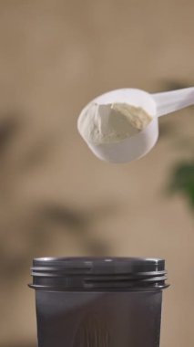 Protein tozu, ölçü kaşığından kabın içine dökülür. beyaz spor beslenmesi. Spor ya da diyet içeceği hazırlamak için kuru karışım.