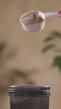 Protein tozu, ölçü kaşığından kabın içine dökülür. beyaz spor beslenmesi. Spor ya da diyet içeceği hazırlamak için kuru karışım.