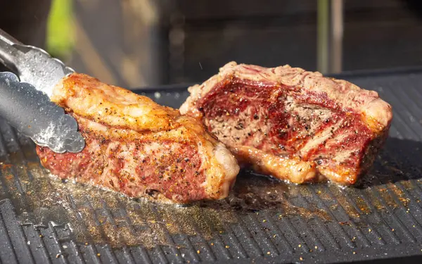 Sıcak elektrikli ızgara yüzeyinde taze ızgara sığır eti ve biftek.